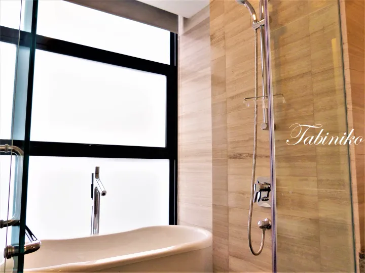 Modern bathroom with a freestanding bathtub, glass shower enclosure, and large window overlooking the outdoors.
