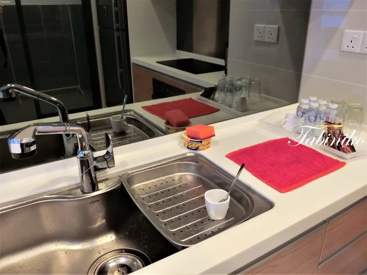 Modern kitchen sink with LIZEN faucet, red towels, and water bottles in a serviced apartment.