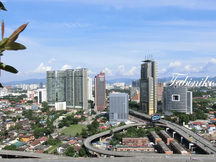 Kuala Lumpur skyline featuring modern high-rise buildings and elevated highways under a blue sky.