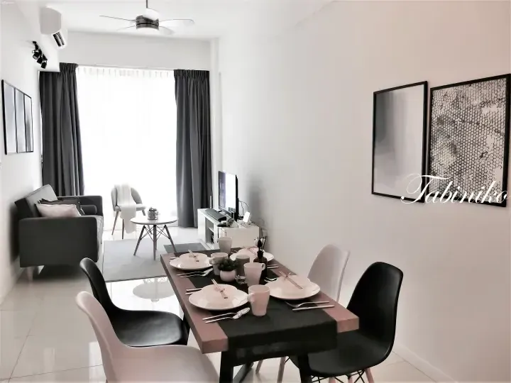 Modern dining area with a wooden table set for four, black and white chairs, and a living room with a grey sofa in the background.
