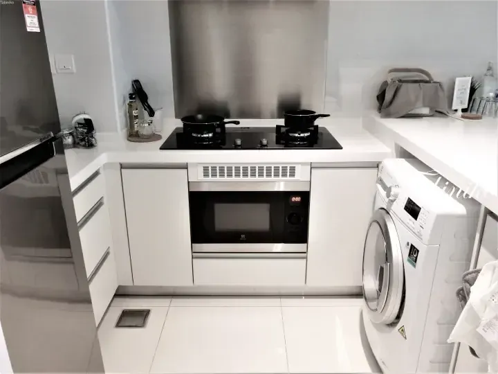 Modern kitchen with white cabinets, stainless steel microwave, gas stove, and washing machine.