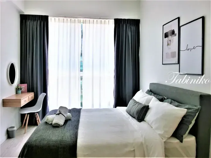 Modern bedroom with grey bed, white linens, and wooden desk near window with sheer curtains