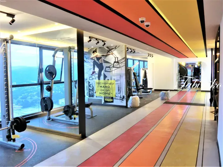 Modern gym interior with Technogym equipment, large windows offering a city view, and motivational wall art.