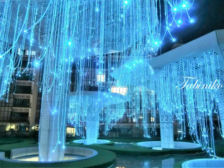 Blue fiber optic light installation hanging from the ceiling at a modern building entrance.