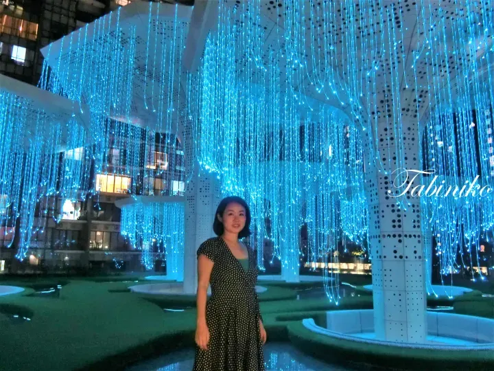 Woman standing under the blue fiber optic light installation at the Pavilion KL atrium.