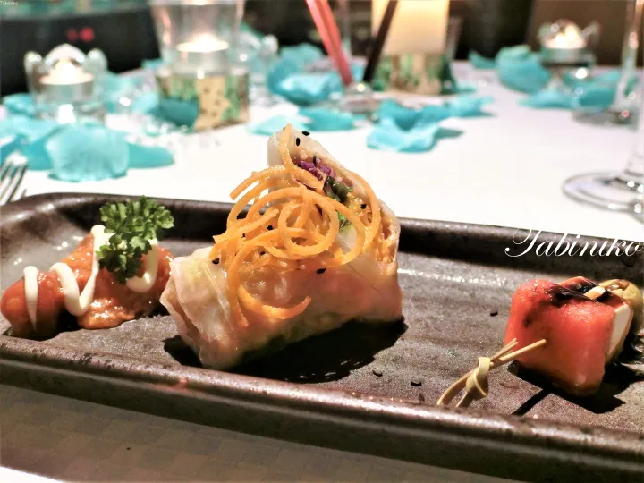 カリカリの細切り野菜をトッピングした春巻きと、ソースをかけた料理が盛り付けられたエレガントなアペタイザープレート。