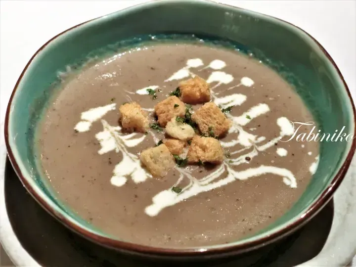 Creamy mushroom soup in a green bowl topped with croutons and cream drizzle