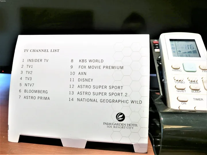 Palm Garden Hotel IOI Resort Cityのテレビチャンネルリストカードとエアコンのリモコン。
