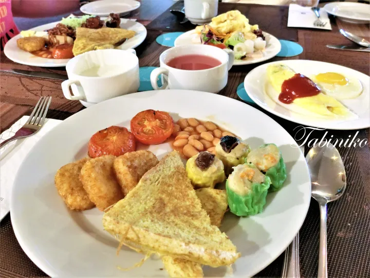 トースト、ハッシュドポテト、豆、トマト、ディンサムが盛られたマレーシアのホテルの朝食ビュッフェのプレート。