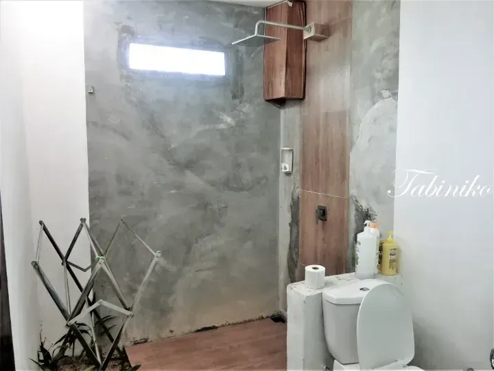 Modern bathroom with concrete walls, wooden accents, and a rainfall shower head in a Malaysia property