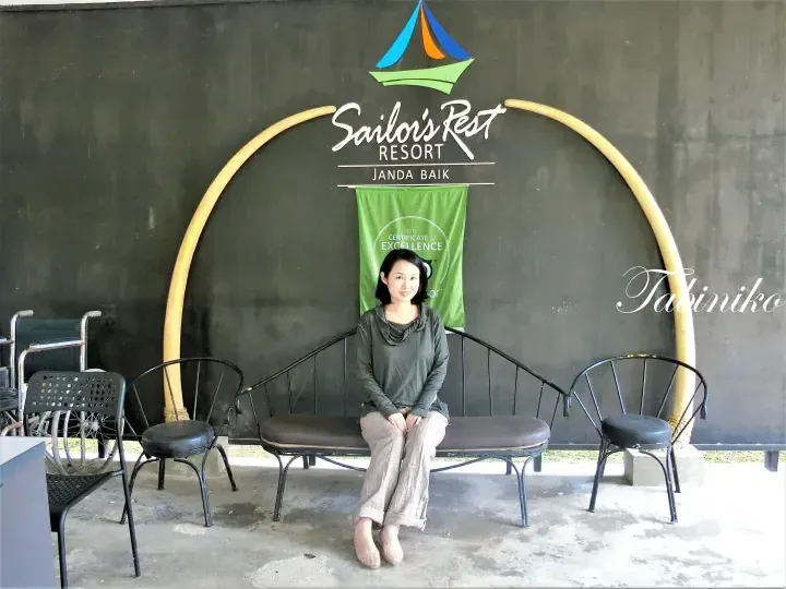 Woman sitting on a bench at Sailor’s Rest Resort Janda Baik with a TripAdvisor Certificate of Excellence banner.