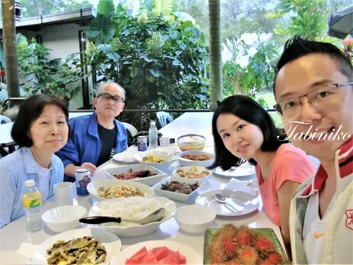 Family enjoying a meal with rambutan and rice at an outdoor restaurant in Malaysia.
