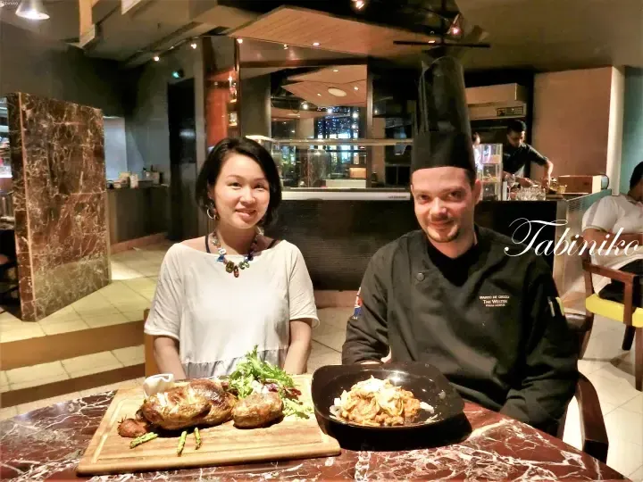 Chef Marco De Cecco and a guest pose with roasted chicken and pasta at The Westin Kuala Lumpur restaurant.