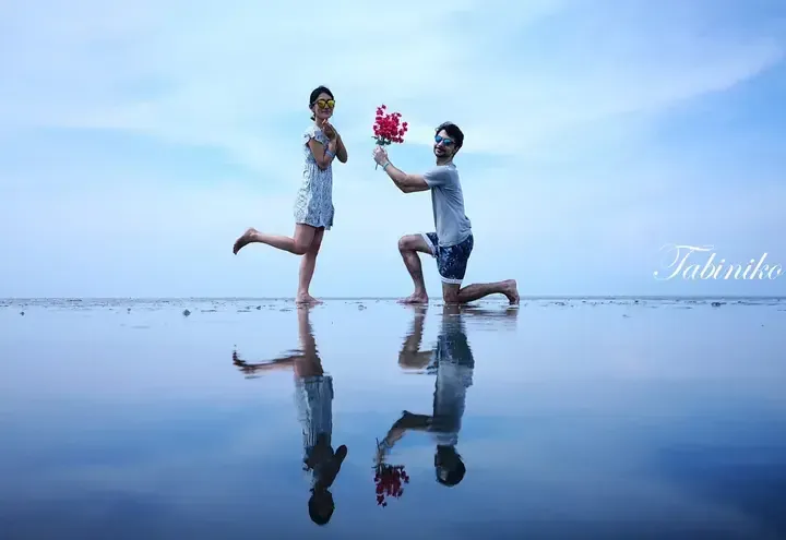 Couple celebrating on a beach with perfect reflections, featuring the Tabiniko watermark.
