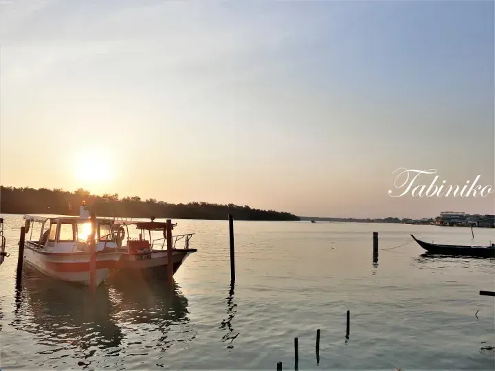 Boats docked at a jetty during sunset with the sun shining through the cabin window.