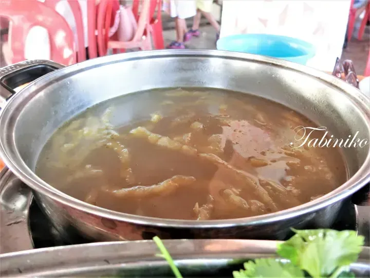 Steaming pot of traditional Malaysian chicken feet soup served in a metal bowl at a local eatery.