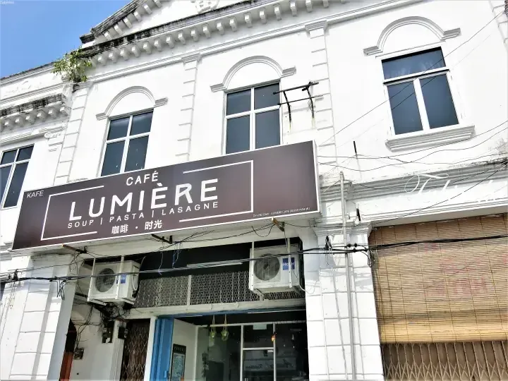 Cafe Lumiere storefront in a white heritage building, featuring a brown sign with soup, pasta, and lasagne offerings.