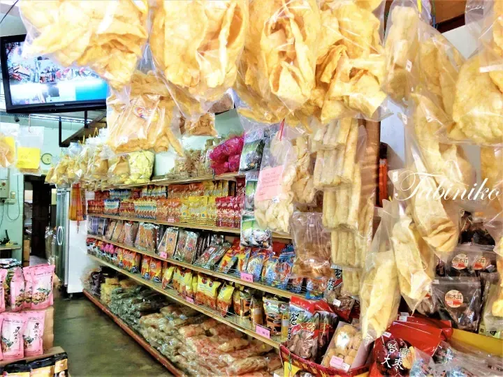Interior of a Malaysian shop displaying hanging dried seafood and packaged snacks on shelves.
