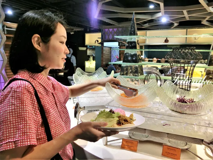 Vivatel Kuala Lumpurのビュッフェで、人参や赤キャベツなどのサラダを選ぶ女性。