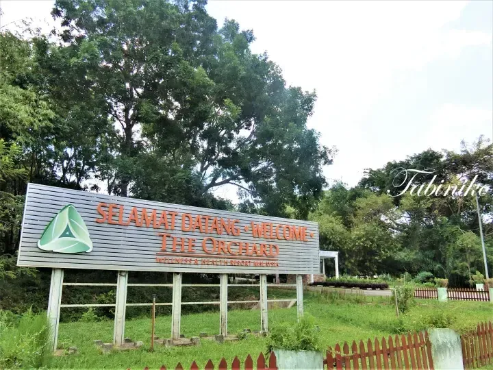 Welcome sign for The Orchard Wellness & Health Resort Malaysia surrounded by lush greenery