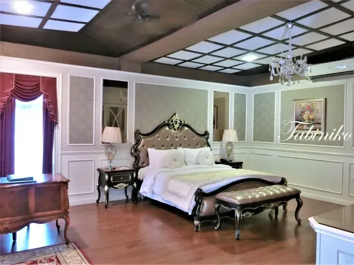 Luxurious bedroom with ornate bed, chandelier, and coffered ceiling at Tabiniko resort in Malaysia.