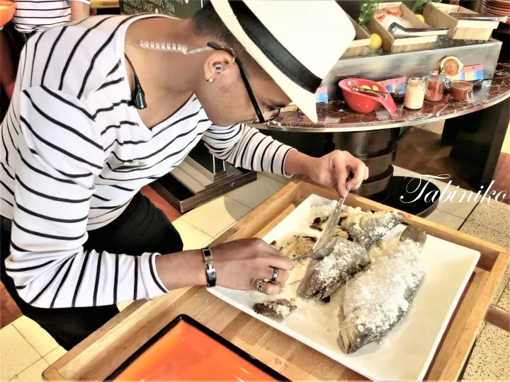 ビュッフェで塩焼きの魚を割るシェフ
