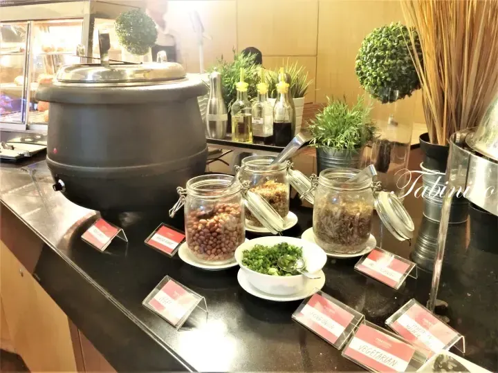 Buffet station at Parkroyal featuring roasted peanuts, fried anchovies, spring onions, and oils with labels.