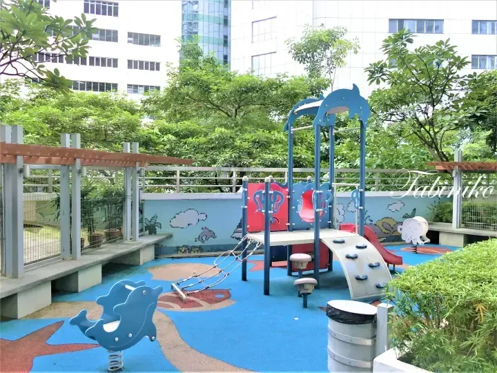 Children’s playground with dolphin-themed equipment and blue flooring at a residential complex in Malaysia