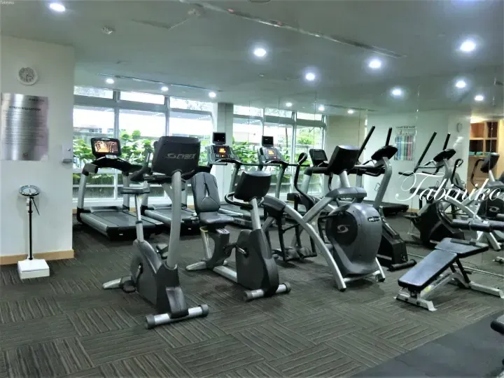 Well-equipped gym with Cybex treadmills, recumbent bikes, and elliptical trainers in a bright room with large windows.