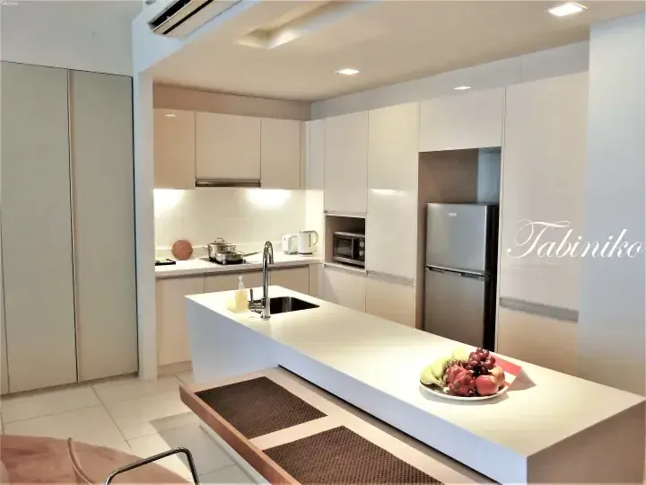 Modern kitchen with white cabinetry, island counter, and fruit bowl in a Malaysian property