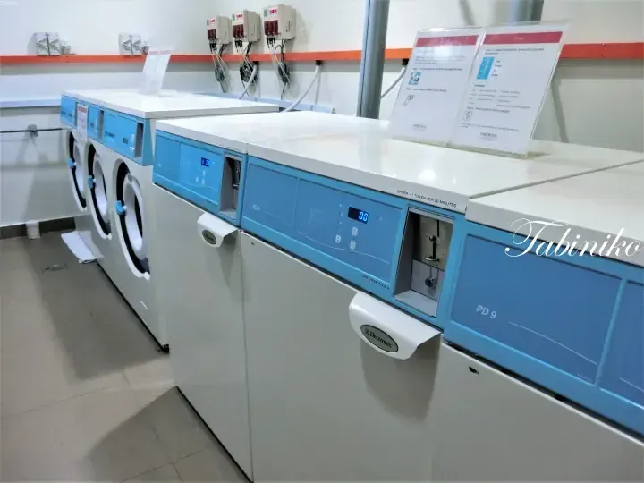 Electrolux dryers and washing machines in a laundry room at Parkroyal Kuala Lumpur, featuring blue control panels and usage instructions.