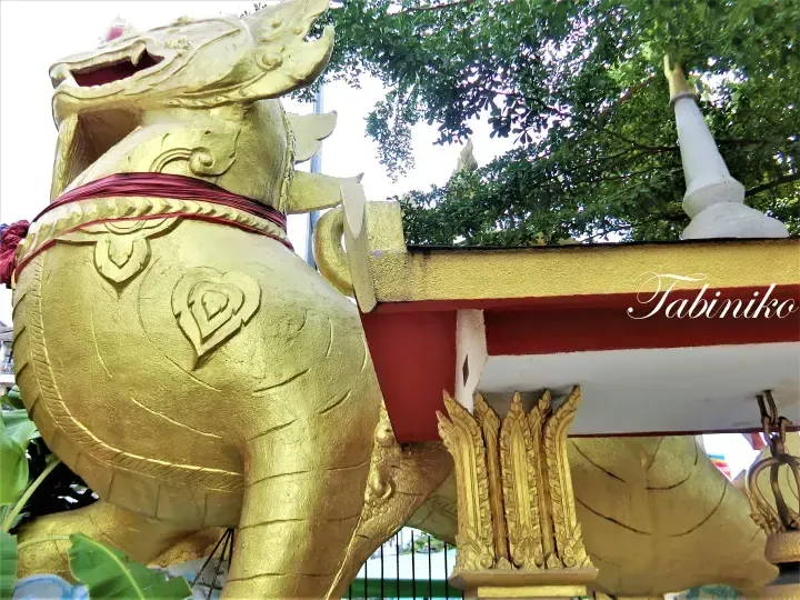 Golden Naga statue guarding a traditional Thai-style temple entrance with intricate details.
