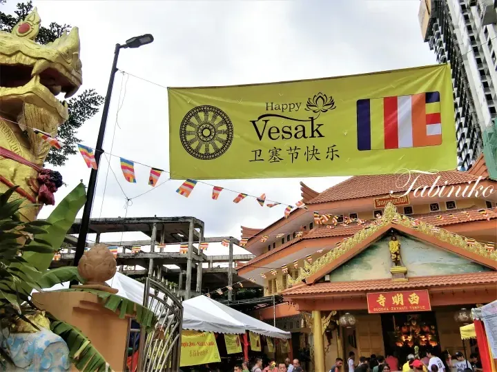 Buddha Jayanti Temple entrance decorated with a Happy Vesak banner and Buddhist flags.