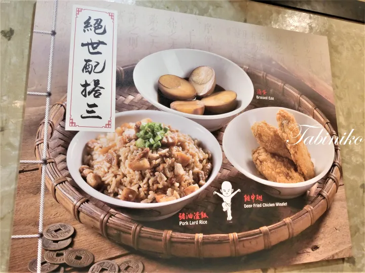 竹籠に盛られた豚脂ご飯、煮卵、唐揚げのメニュー写真。中国語の書道看板が添えられている。