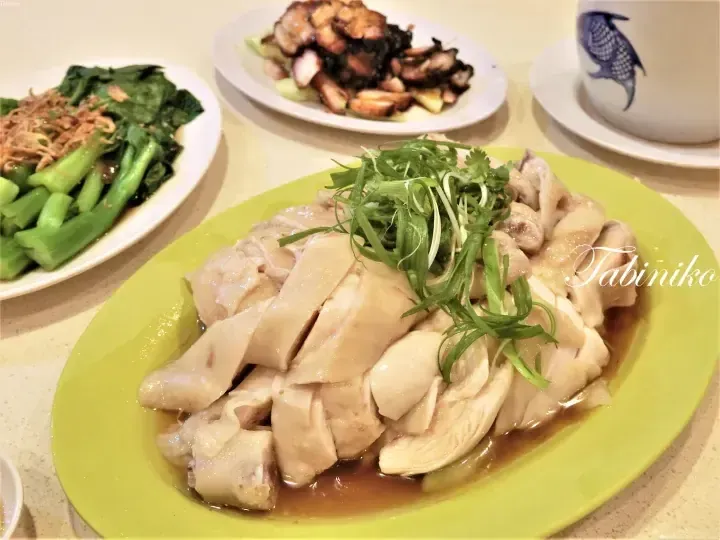 Hainanese chicken rice served with Chinese broccoli and char siu at a Malaysian hawker centre.