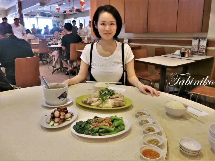 マレーシアのレストランで海南鶏飯や焼豚を囲む女性。