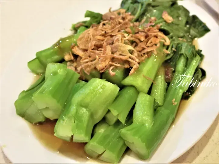 Steamed Chinese broccoli with garlic sauce and crispy shallots on a white plate