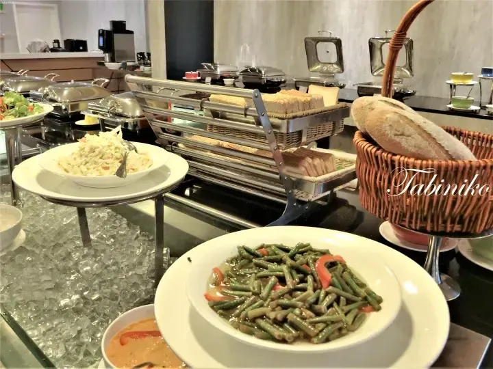 Buffet spread featuring fresh green beans, coleslaw, and bread baskets at a hotel dining area.