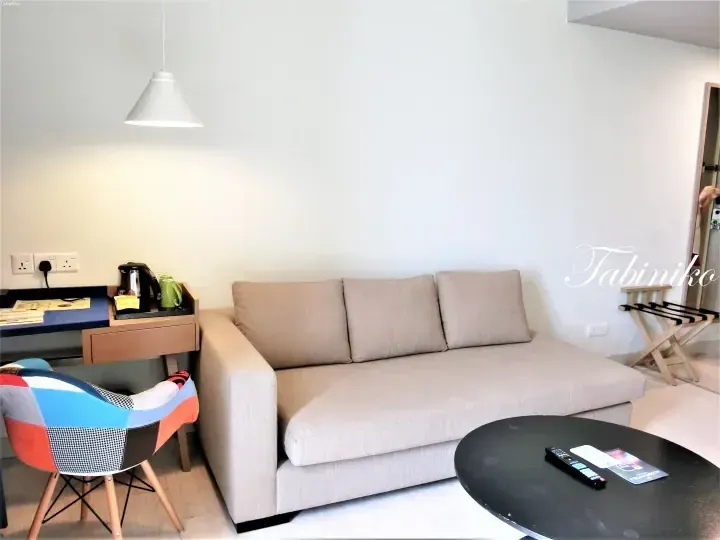 Modern hotel living room with beige sofa, colorful chair, and coffee station at KCOON Hotel