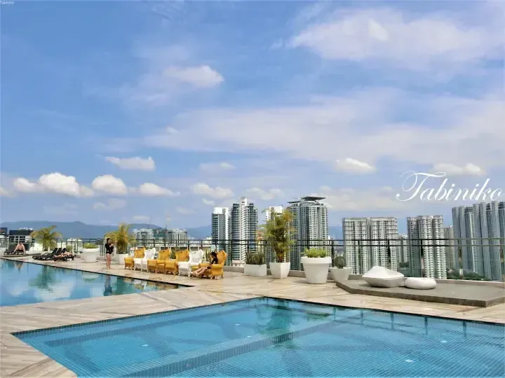 Rooftop infinity pool with yellow lounge chairs overlooking Kuala Lumpur skyline and mountains