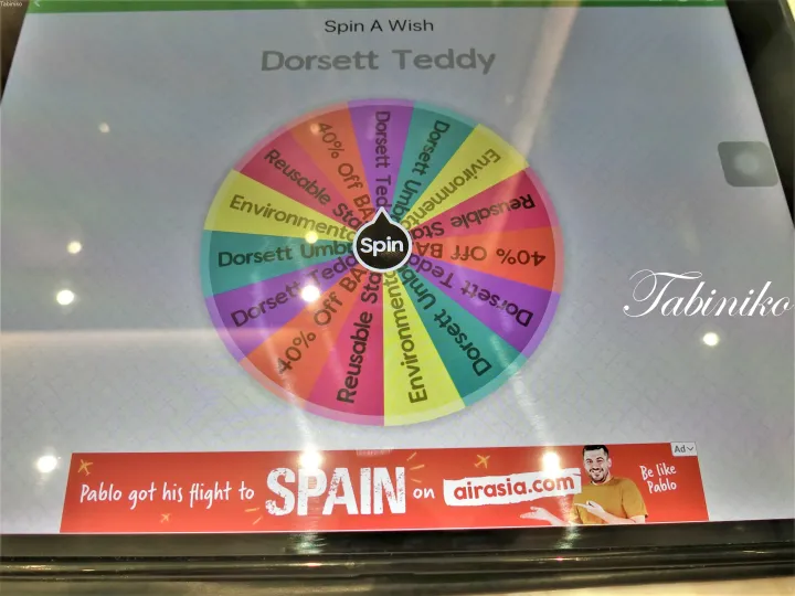 Dorsett Teddlyのプロモーション用ルーレットと、スペイン行きのフライトを宣伝するAirAsiaの広告バナー。