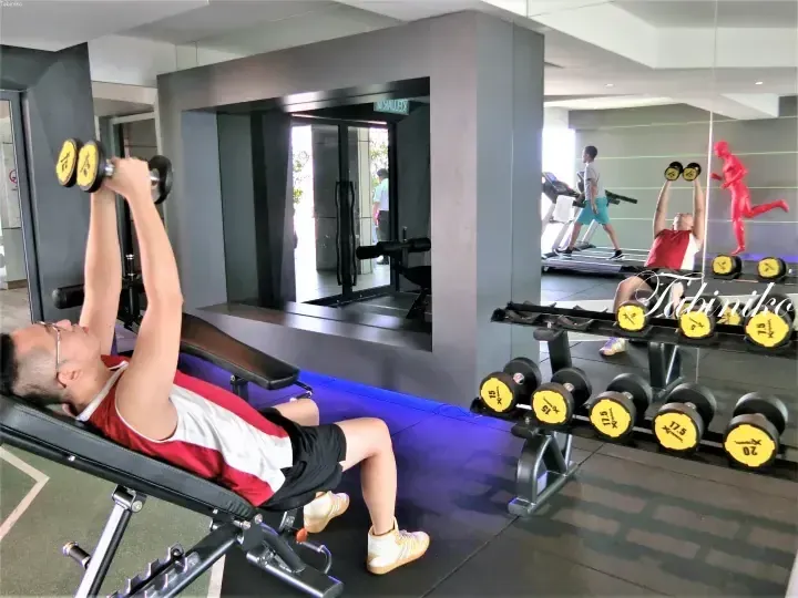 Man doing incline dumbbell press at gym with X-Track weights and mirror reflection.