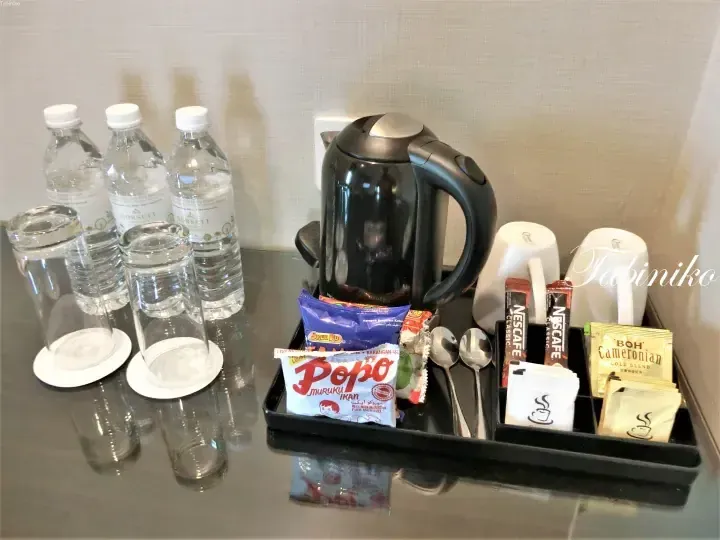 Dorsett hotel minibar setup with water bottles, kettle, Nescafe, BOH Cameronian tea, and Popo snacks.