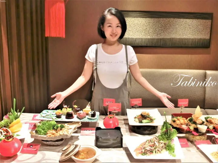 黒胡椒ビーフや dumplings など、豪華な旧正月ビュッフェ料理を披露する女性。