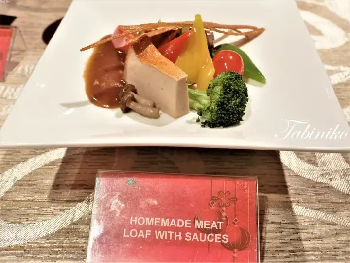 Homemade Meat Loaf with Sauces served on a white plate with vegetables at a hotel buffet.