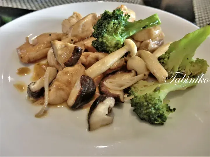 Stir-fried chicken with broccoli, shiitake mushrooms, and enoki mushrooms served on a white plate.