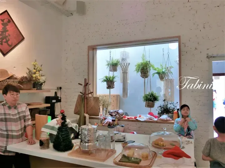 Tabiniko咖啡馆内部，展示着白色砖墙、悬挂植物以及摆放着传统小吃和萨摩瓦尔的柜台。