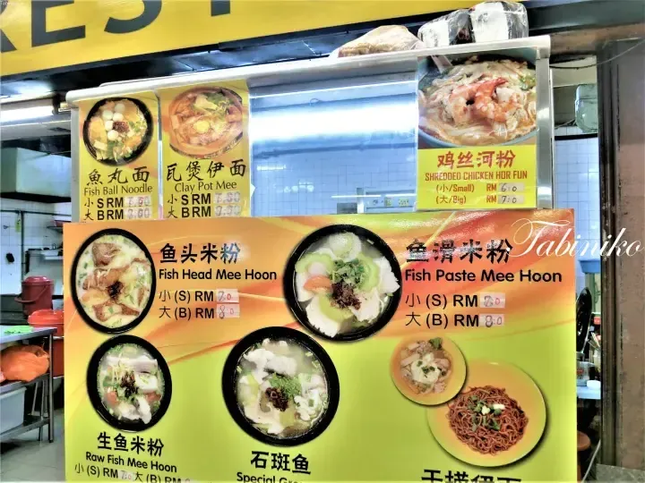 Menu board displaying various Malaysian noodle dishes with prices in Ringgit, including Fish Ball Noodle and Clay Pot Mee.