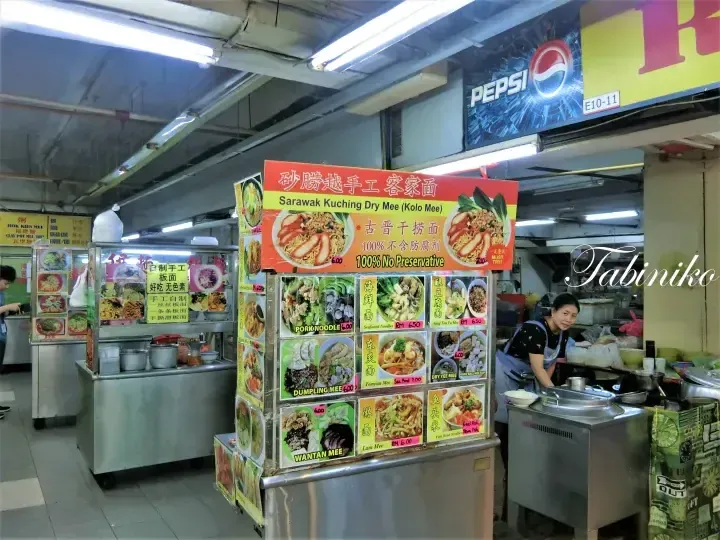 Sarawak Kuching Dry Mee stall menu board displaying noodle options and prices at a local Malaysian food court.