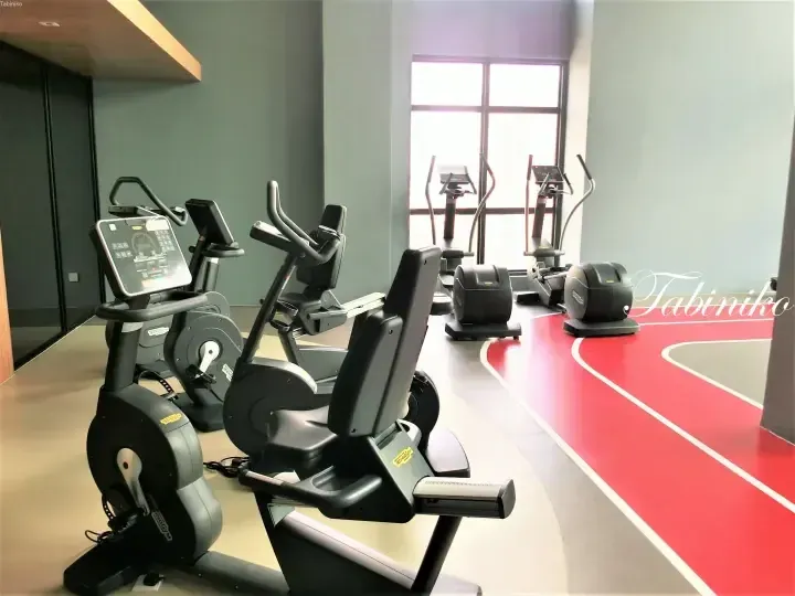 Technogym cardio machines and a red running track in a modern gym with large windows